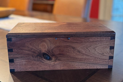 Wooden box on a glass table with a red wall and chair in the background